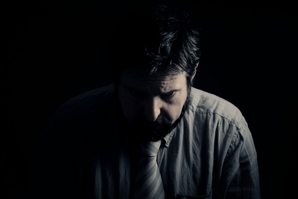 A sad, depressed man, sitting alone in the darkness. Bad feelings, human emotions, the face of depression, having complex thoughts and tough decisions to take. This is a better version of my 1st upload.